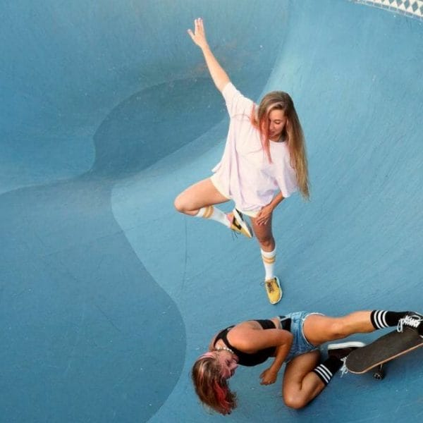 Two Women Skateboarding In A Skate Park.