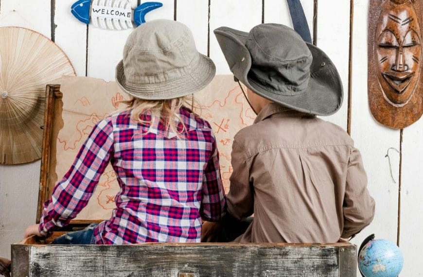 Two Children In Hats Sitting In A Wooden Crate.