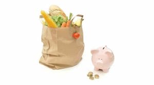 A Piggy Bank Next To A Shopping Bag With Vegetables.