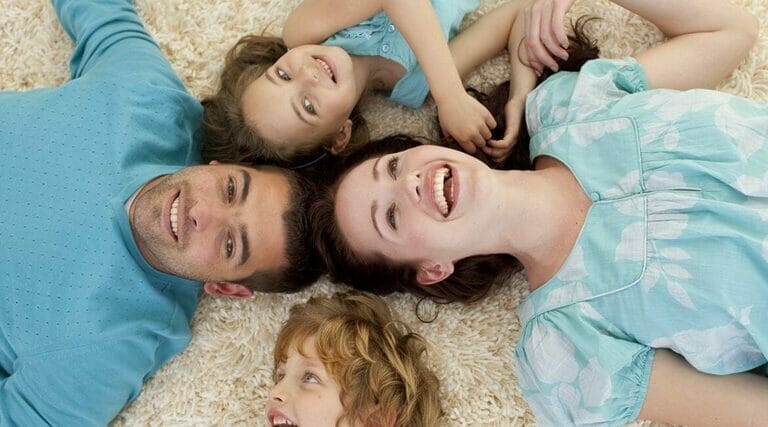 A Family Laying On A White Carpet.
