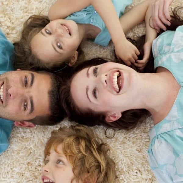 A Family Laying On A White Carpet.